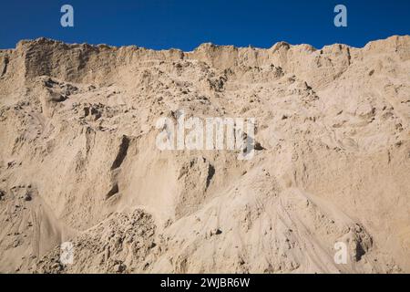 Hügel aus feinem hellbraunem Sand gegen blauem Himmel auf der Baustelle. Stockfoto