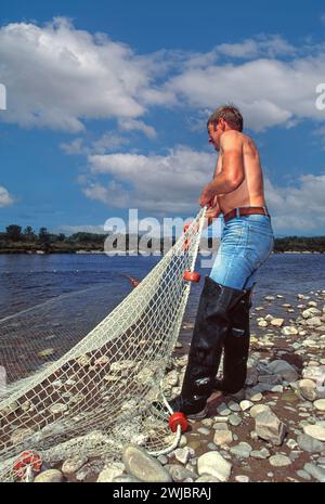 Lachsnetze am Fluss Spey bei Tugnet ein einsamer Fischer, der im Sommer das Netz zieht Stockfoto
