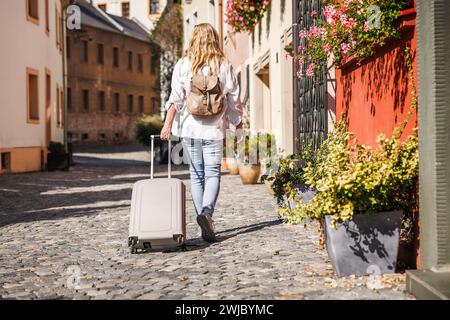 Frau Touristin mit Koffer und Rucksack, die auf der Straße in Olomouc, Tschechien, läuft. Alleinreisende Stockfoto