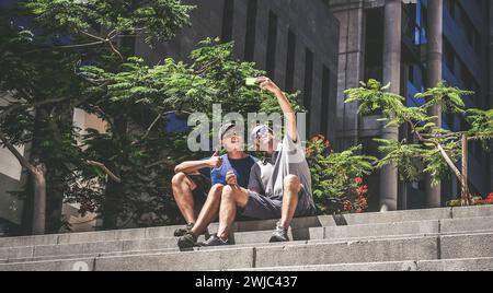 Vater und Sohn nutzen gemeinsam ein Smartphone. Lächelnde Menschen machen Selfie. Junge und Mann genießen Videoanrufe mit Freunden auf dem Mobiltelefon. Technologie, Leben Stockfoto