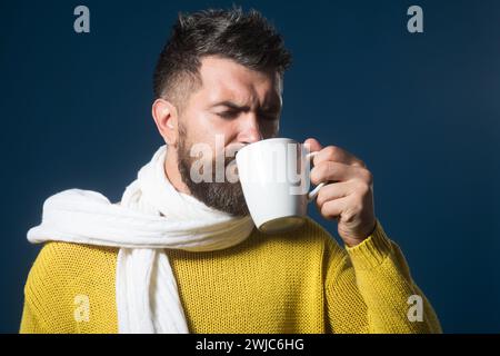 Bärtiger Mann, der eine Tasse heißen Tee im Café genießt. Zufriedener attraktiver Mann, der heißes Getränk trinkt. Kaffeepause. Gutaussehender Mann mit Bart und Schnurrbart Stockfoto