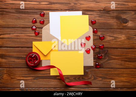 Umschläge mit leeren Karten, Herzen und Band auf hölzernem Hintergrund. Valentinstag-Feier Stockfoto