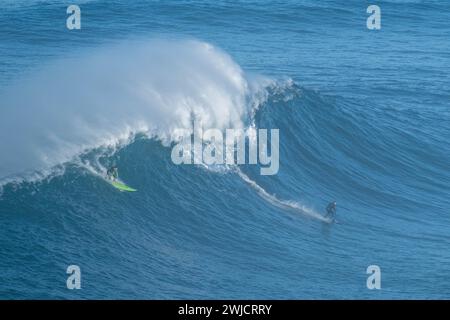 Zwei Surfer, die gleichzeitig eine große Welle reiten, Nazare, Portugal Stockfoto
