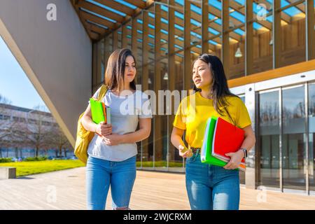 Frontalporträt zweier junger multiethnischer Freunde, die auf dem Universitätscampus plaudern Stockfoto