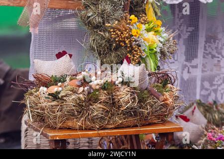 Osterdekoration auf dem Bauernmarkt, Nest aus trockenem Gras, Eiern, Stoffhennen und getrockneten Blumenringen auf dem Bauernmarkt in Prag Stockfoto