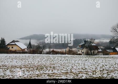 Einige Häuser liegen auf einem schneebedeckten Hügel mit majestätischen Bergen im Hintergrund Stockfoto