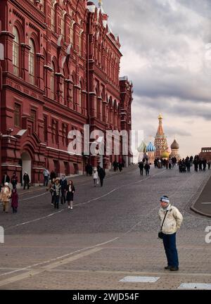 Ein Tourist, der an der Hauptzugangsstraße zum Roten Platz Moskaus mit St. Basilius Kathedrale im Hintergrund beleuchtet von der Abendsonne Stockfoto