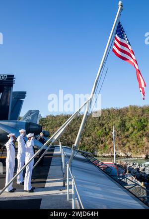 APRA HARBOR, Guam (14. Februar 2024) US-Seeleute grüßen die US-Flagge während der Morgenfarben an Bord des Flugzeugträgers USS Theodore Roosevelt (CVN 71), 14. Februar 2024. Theodore Roosevelt, Flaggschiff der Carrier Strike Group Nine, ist derzeit Pier Side im APRA Harbor, Guam, für einen geplanten Hafenbesuch. Als integraler Bestandteil der US-Pazifikflotte betreibt die 7. Flotte Marine im Indopazifik und bietet die realistische und relevante Ausbildung, die erforderlich ist, um die Rolle der US-Navy im gesamten Spektrum militärischer Operationen – von Kampfeinsätzen bis hin zu humanitärer Hilfe und – wahrzunehmen Stockfoto