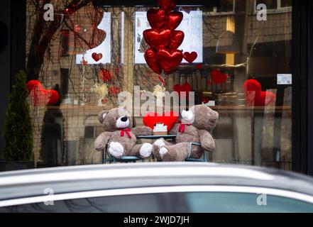 Nicht exklusiv: KIEW, UKRAINE - 14. FEBRUAR 2024 - zwei Teddybären werden an einem Tisch mit herzförmigen roten Ballons vor einem Café auf Valen gesehen Stockfoto