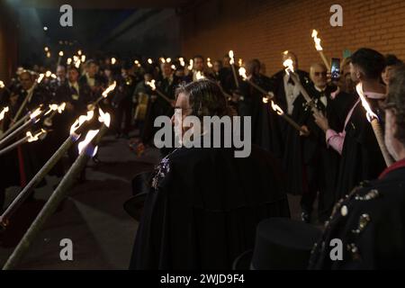 Madrid, Madrid, Spanien. Februar 2024. Mitglieder der Sardinenbruderschaft werden während der Prozession mit Fackeln beleuchtet. Die Sardinenprozession, die in Madrid stattfindet, ist eine jahrhundertealte spanische Tradition, die durch ein Gemälde des spanischen Künstlers Francisco de Goya, das Begräbnis der Sardinen, berühmt wurde. Es markiert das Ende der Karnevalsfeiern und den Beginn der Fastenzeit 40 Tage vor Ostern. Es besteht aus einer Prozession, die eine Beerdigung parodiert, bei der eine symbolische Figur einer Sardine in ihrem Sarg verbrannt wird. Das fest findet jeden Aschermittwoch statt und symbolisiert Stockfoto