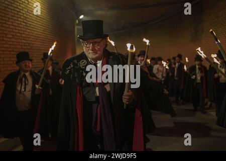 Madrid, Madrid, Spanien. Februar 2024. Mitglieder der Sardinenbruderschaft werden während der Prozession mit Fackeln beleuchtet. Die Sardinenprozession, die in Madrid stattfindet, ist eine jahrhundertealte spanische Tradition, die durch ein Gemälde des spanischen Künstlers Francisco de Goya, das Begräbnis der Sardinen, berühmt wurde. Es markiert das Ende der Karnevalsfeiern und den Beginn der Fastenzeit 40 Tage vor Ostern. Es besteht aus einer Prozession, die eine Beerdigung parodiert, bei der eine symbolische Figur einer Sardine in ihrem Sarg verbrannt wird. Das fest findet jeden Aschermittwoch statt und symbolisiert Stockfoto