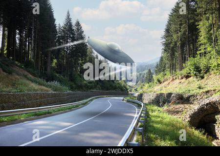 Ein außerirdisches Raumschiff fliegt in Bergen über die Straße. UFO Stockfoto