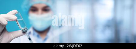 Arzt füllt Spritze mit Medikamenten aus Glasfläschchen auf verschwommenem Hintergrund, Großaufnahme. Bannerdesign Stockfoto