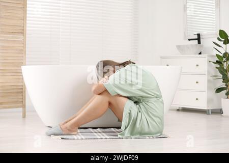 Wechseljahre. Deprimierte Frau in der Nähe der Badewanne im Badezimmer Stockfoto