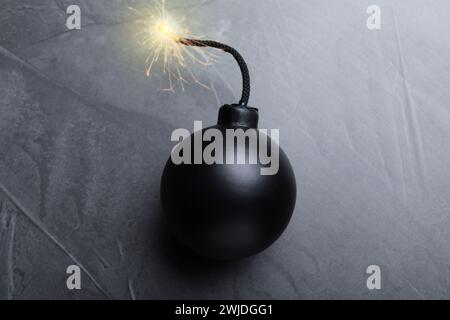 Altmodische schwarze Bombe mit beleuchteter Sicherung auf grauem Tisch, Draufsicht Stockfoto