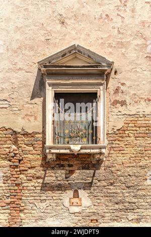 Vintage-Fenster mit Eisengitter auf verwitterter Ziegelmauer Stockfoto