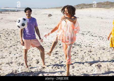 Ein junges birassisches Paar genießt ein Fußballspiel am Strand Stockfoto