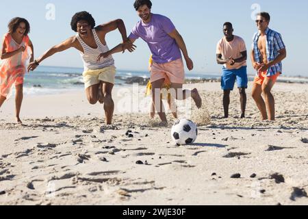 Diverse Freunde spielen am Strand Fußball Stockfoto