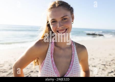 Junge kaukasische Frau lächelt an einem sonnigen Strandtag hell Stockfoto