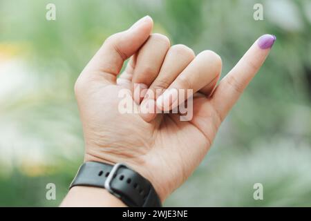Ein indonesischer Mann zeigt einen kleinen Finger, der mit Tinte bedeckt ist, nachdem er die Wahl oder Pemilu abgegeben hat Stockfoto