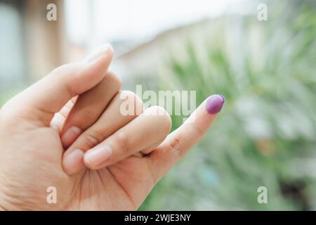 Ein indonesischer Mann zeigt einen kleinen Finger, der mit Tinte bedeckt ist, nachdem er die Wahl oder Pemilu abgegeben hat Stockfoto