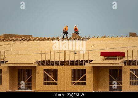 Dachüberdachung. Dachbauer installieren neues Dach. Bauarbeiter, die eine große Dachwohnung überdacht haben. Zimmermann arbeitet Stockfoto