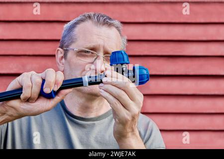 Montage der externen Trinkwasserversorgung in ländlichen Gebieten, man steckte das Ende des HDPE-Rohrs in das Loch der dreifachen Kompressionsverschraubung. Stockfoto