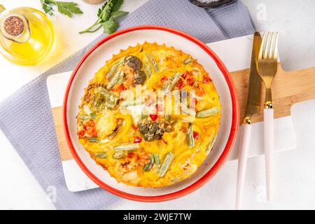 Hausgemachte Gemüseauflauf Frittata, gesunde vegetarische Speisen, Bratpfanne oder im Ofen gebackenes Eieromelette mit Gemüse auf weißem Marmor Küchentisch Co Stockfoto