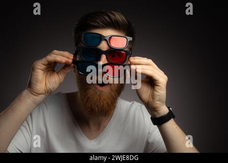 Coole, verspielte junge brünette bärtige Mann in drei Paaren bunter Brillen Stockfoto