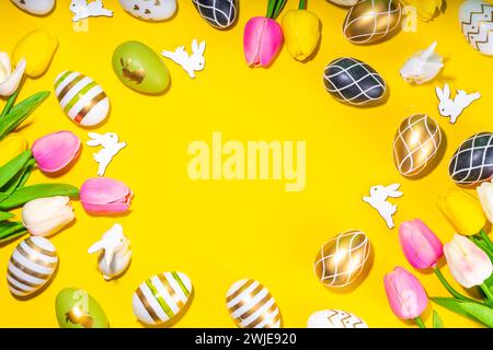 Leuchtender Hintergrund für Ostergrußkarte. Schicke schwarze, goldene, gestreifte Ostereier mit weißen Hasen, Tulpenblüten oben... Stockfoto