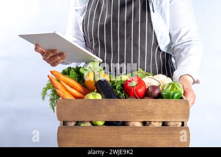 Bauernhof-Bio-Markt-Shopping-Konzept, Holzkiste mit Sommer, rohem Gemüse und Obst im Herbst, in den Händen von Bauernfrauen auf weißem Hintergrund Stockfoto