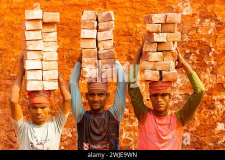 Dhaka, Dhaka, Bangladesch. Februar 2024. Arbeiter tragen in einem Ofen in Dhaka, Bangladesch, Steine mit einem Gewicht von mehr als 20 kg auf dem Kopf. Die Arbeiter '''', die weniger als Â£1 pro Schicht ''''' erhalten, bewegen bis zu 2.500 Steine pro Tag unter heißen Bedingungen. Rund 4 00.000 einkommensschwache Migranten kommen jedes Jahr aus verschiedenen Teilen des Landes nach Dhaka, um in brickfields zu arbeiten. Lange Arbeitszeiten unter sengender Sonne auf den Ziegelfeldern, massive Staubansammlungen, Sturzgefahr von LKW und Ziegelhaufen und das Tragen übermäßiger Lasten stellen eine ernste Gesundheitsgefährdung für die W dar Stockfoto