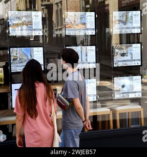 Immobilienagentur in Paris (Frankreich). Ein Paar, das sich die geheime Werbung durch das Fenster ansieht Stockfoto