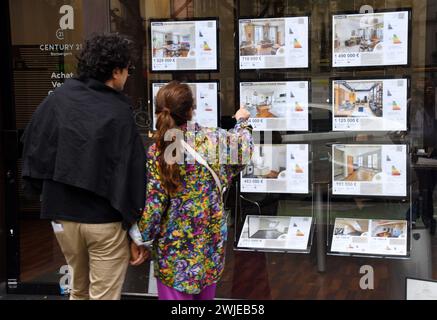 Immobilienagentur in Paris (Frankreich). Ein Paar, das sich die geheime Werbung durch das Fenster ansieht Stockfoto