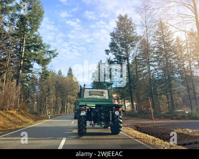 Breitenbrunnen, Deutschland - 27. Dezember 2023: Die Fahrerperspektive eines grünen Unimog-Lkw, der eine Straße durch einen üppigen Wald unter klarem blauem Himmel fährt Stockfoto