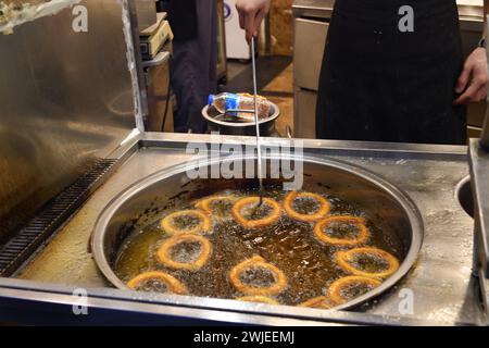 Ein Koch kocht die traditionellen Halka Tatlisi oder türkischen Churros in einem Street Food Shop. Ein knuspriges und süßes Streetdessert, das in Zitronen getränkt ist Stockfoto