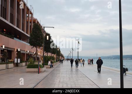Istanbul, Türkei - 11. Dezember 2023: Die Menschen spazieren abends auf dem Stadtdamm. Galataport Promenade Stockfoto