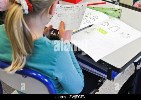 Arvieux, Departement Hautes-Alpes (Französische Alpen), Queyras: Grundschulklasse. Das Schulmädchen sitzt an ihrem Schreibtisch und schreibt in ihr Übungsbuch Stockfoto