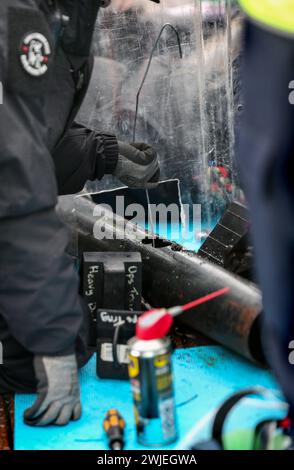 Spezialpolizisten des Schneidteams verwenden Draht in gebohrten Löchern, um Ketten zwischen Demonstranten zu haken, damit sie sie während des Protestes freilassen können. Unterstützer der Palästinensischen Aktion blockieren den einzigen Fahrzeugzugang zur israelischen Verteidigungsfirma, dem Geschäft von Elbit Systems in Aztec West, Bristol. Sie argumentieren, dass die von Elbit in Großbritannien hergestellten Waffen von der israelischen Verteidigungsstreitkräfte gegen Palästinenser in Gaza und anderswo eingesetzt werden. Bei den israelischen Bombenanschlägen im Gazastreifen sind seit Oktober 2023 mehr als 30.000 Palästinenser ums Leben gekommen. Die Palästinensische Aktion ist entschlossen, unerbittlich zu verharren Stockfoto