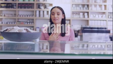 Eine junge, birassische Frau steht hinter einer Theke in einem Laden Stockfoto