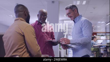 Ein ranghoher Afroamerikaner spricht mit Kollegen in einem Büro Stockfoto