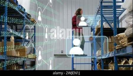 Bild von Ikonen und Datenverarbeitung über kaukasische Frau, die im Lager arbeitet Stockfoto