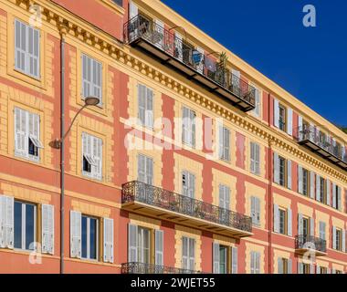 Schicke Apartments an der Küste von Nizza, an der französischen Riviera - Cote d'Azur, Frankreich. Herrliche Ockerfarben mit blau-grauen Fensterläden. Stockfoto