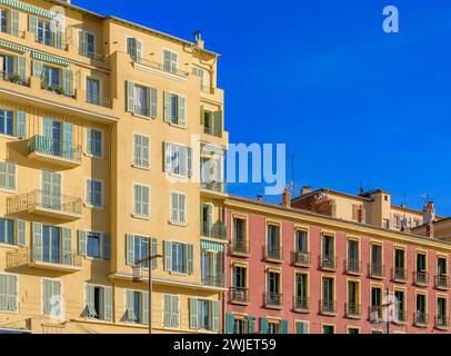 Blick auf die schicken Apartments mit Blick auf Port Lympia in Nizza, an der französischen Riviera - Cote d'Azur, Frankreich. Ockerfarben mit graugrünen Fensterläden. Stockfoto