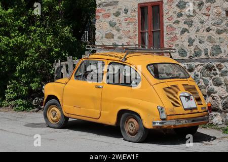 347 klassisches Zastava Z750 LE von 1980, orange-gelb gefärbtes, sogenanntes Fikjo-Auto, parkt vor einem Volkshaus. Vevchani-Nordmazedonien. Stockfoto