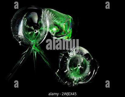 Glasrisse. Kugellöcher mit grünen Reflexen im Glas auf schwarzem Hintergrund. Makro. Seitenansicht. Stockfoto