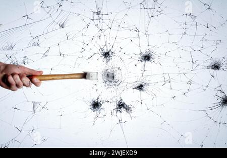 Risse im Fenster. Hammer schlägt auf Glas. Kreatives Konzept. Stockfoto