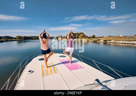 Aigues-Mortes (Südfrankreich): Tourismus auf dem „Kanal der Rhone a Sete“ (Kanal der Rhone-Sete). Zwei Frauen üben Yoga auf einem Kanalkahn Stockfoto