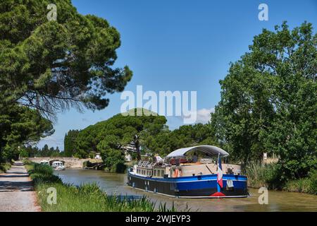 Fahren Sie an Bord der Hotelkahn „L’Esperance“ auf dem Canal du Midi. Touristen genießen die Sonne auf dem Deck des Hotelkahns, in der Nähe der Schleuse von Homps ( Stockfoto