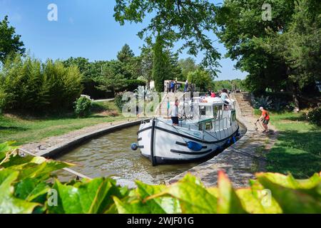 Flusstourismus auf dem Canal du Midi bei der Schleuse Aiguille. Mietkahn, der durch die Schleuse fährt. Der Canal du Midi ist als UNESCO World Heri eingetragen Stockfoto